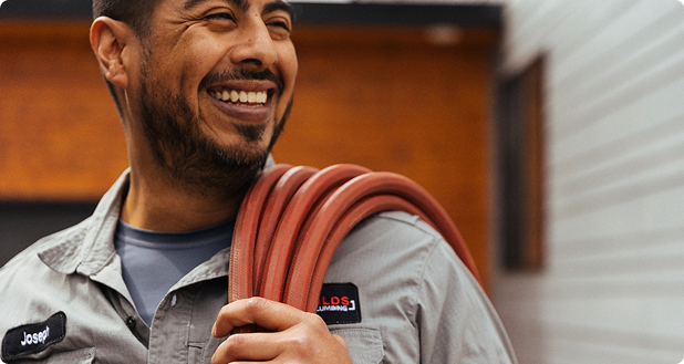 man with an orange hose standing in front of a house