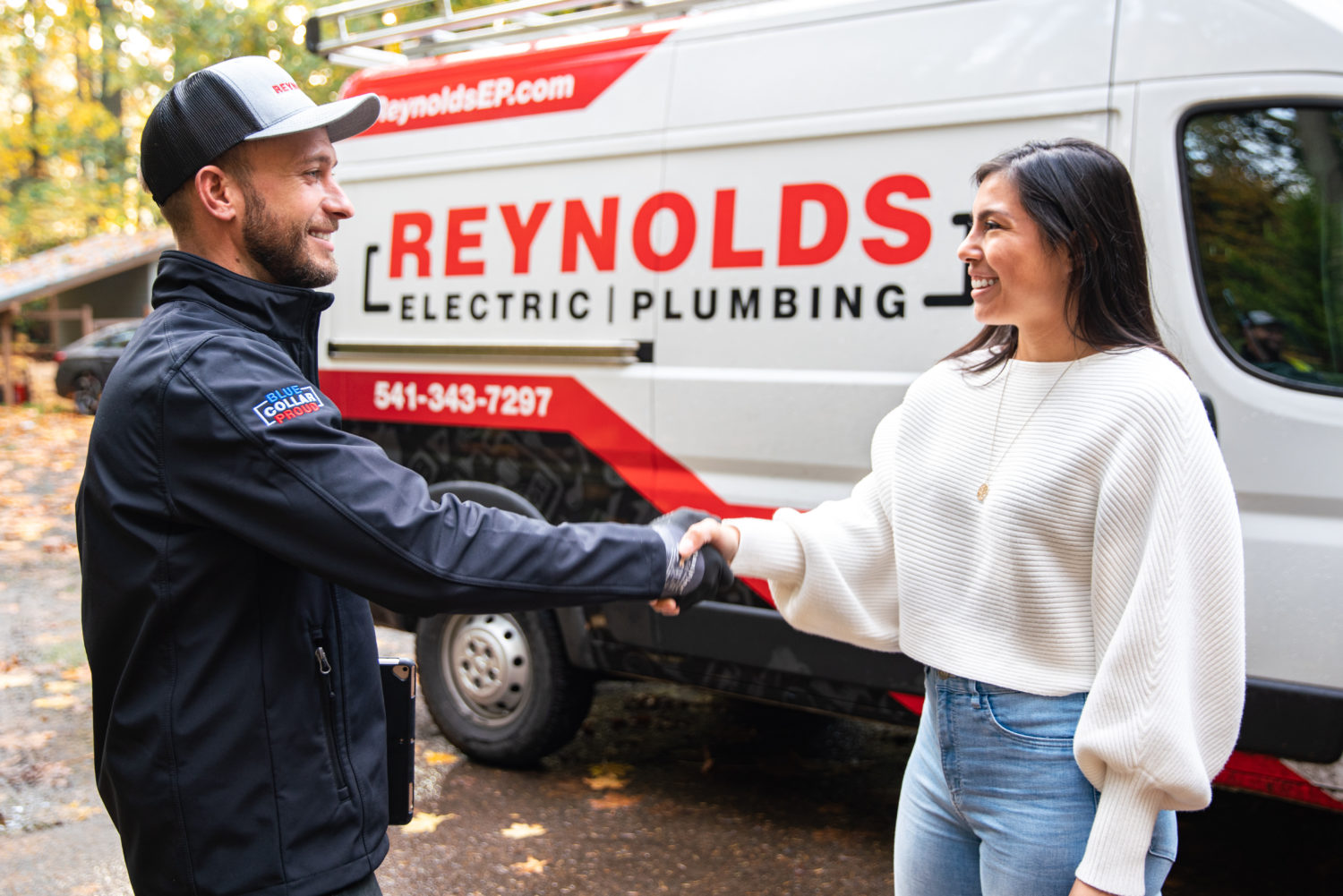 Homeowner shaking hands with Reynolds technician with Reynolds service truck in the background.