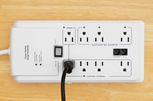 A strip surge protector placed on a wood surface.