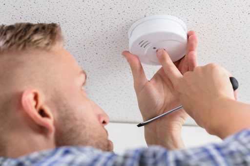 A man pressing a button on a carbon monoxide detector.