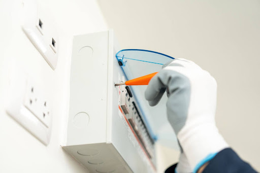 Reynolds electrician using screwdriver for circuit breaker